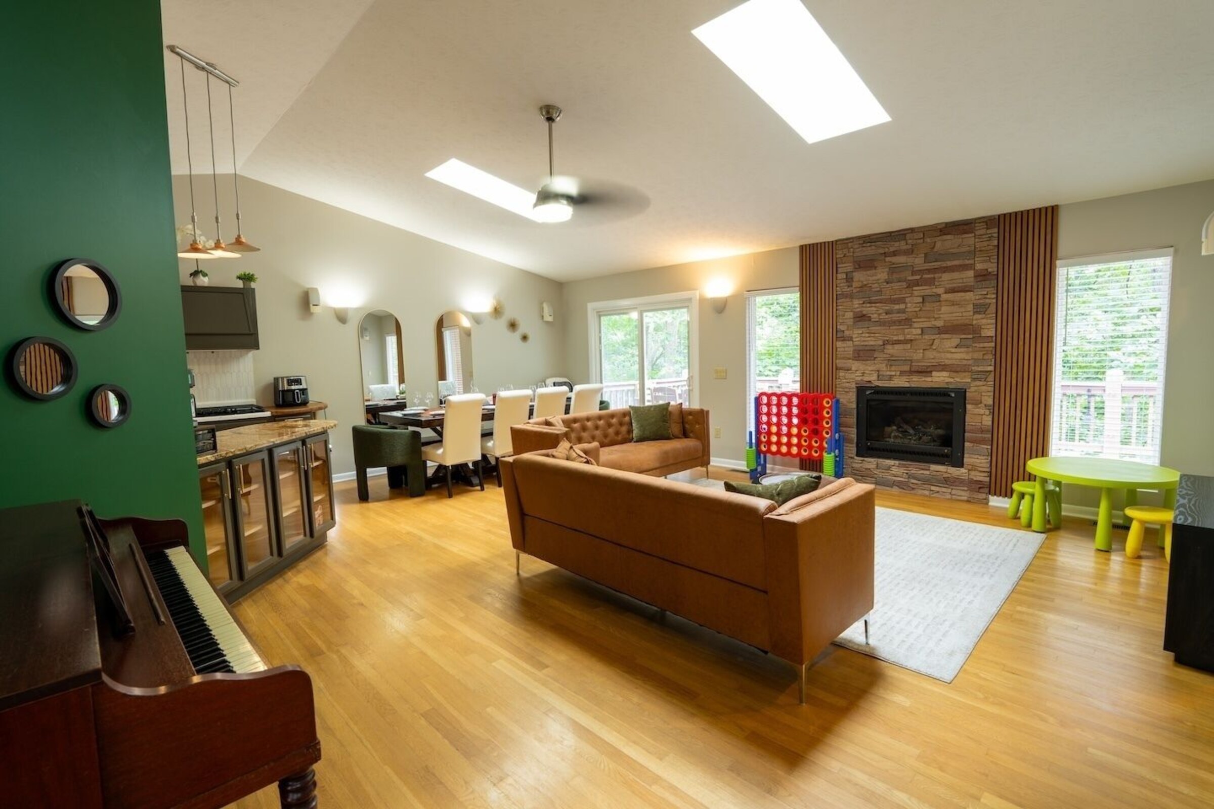 Living room with piano, sectional seating and stone fireplace